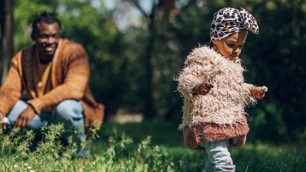 A parent looks at his daughter from a slight distance as they explore the outdoors. | Image: Imani Montessori School